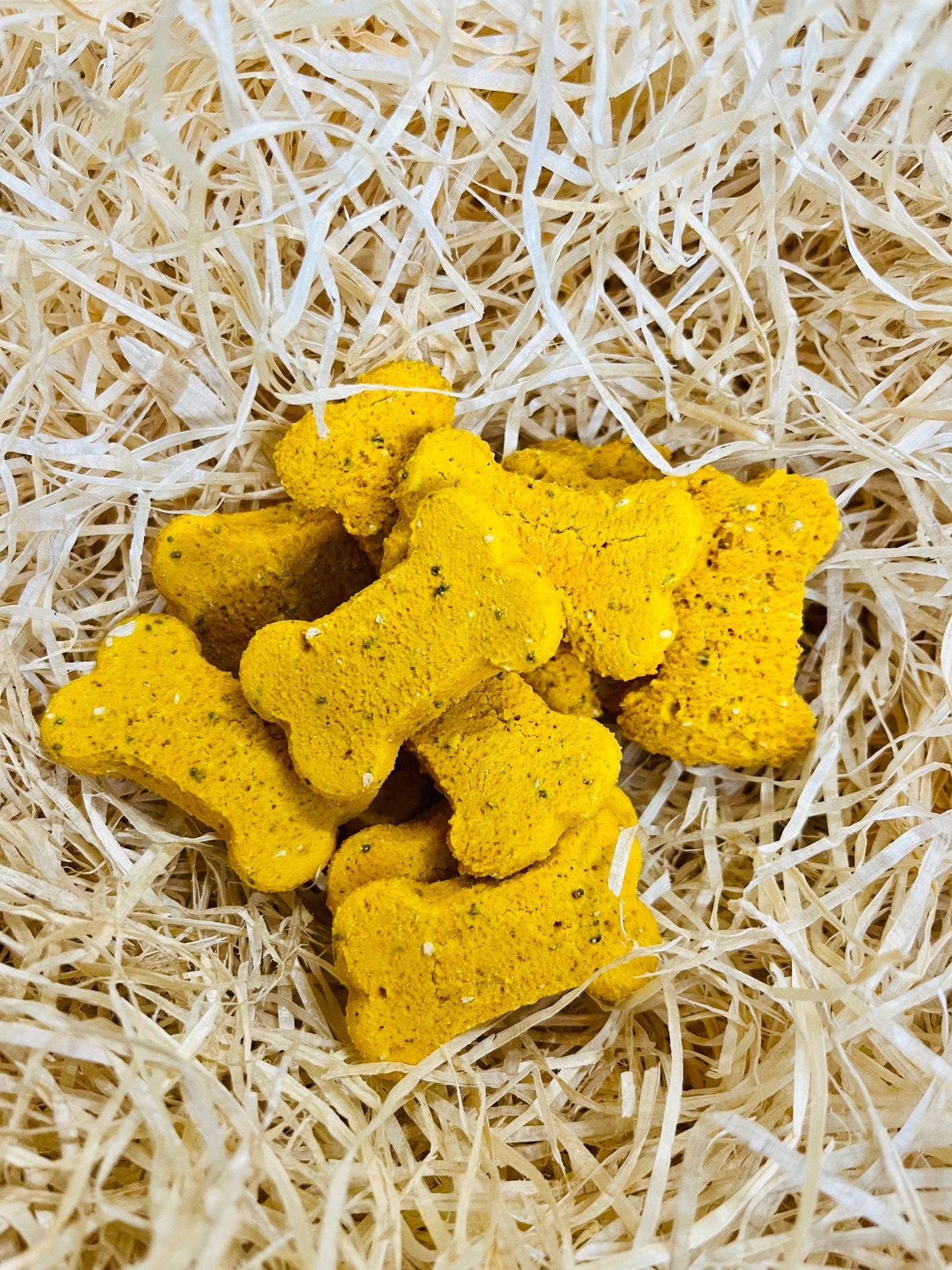 Hip & Joint Bones dog treats displayed loose, crunchy bone-shaped biscuits with turmeric and chia seeds.