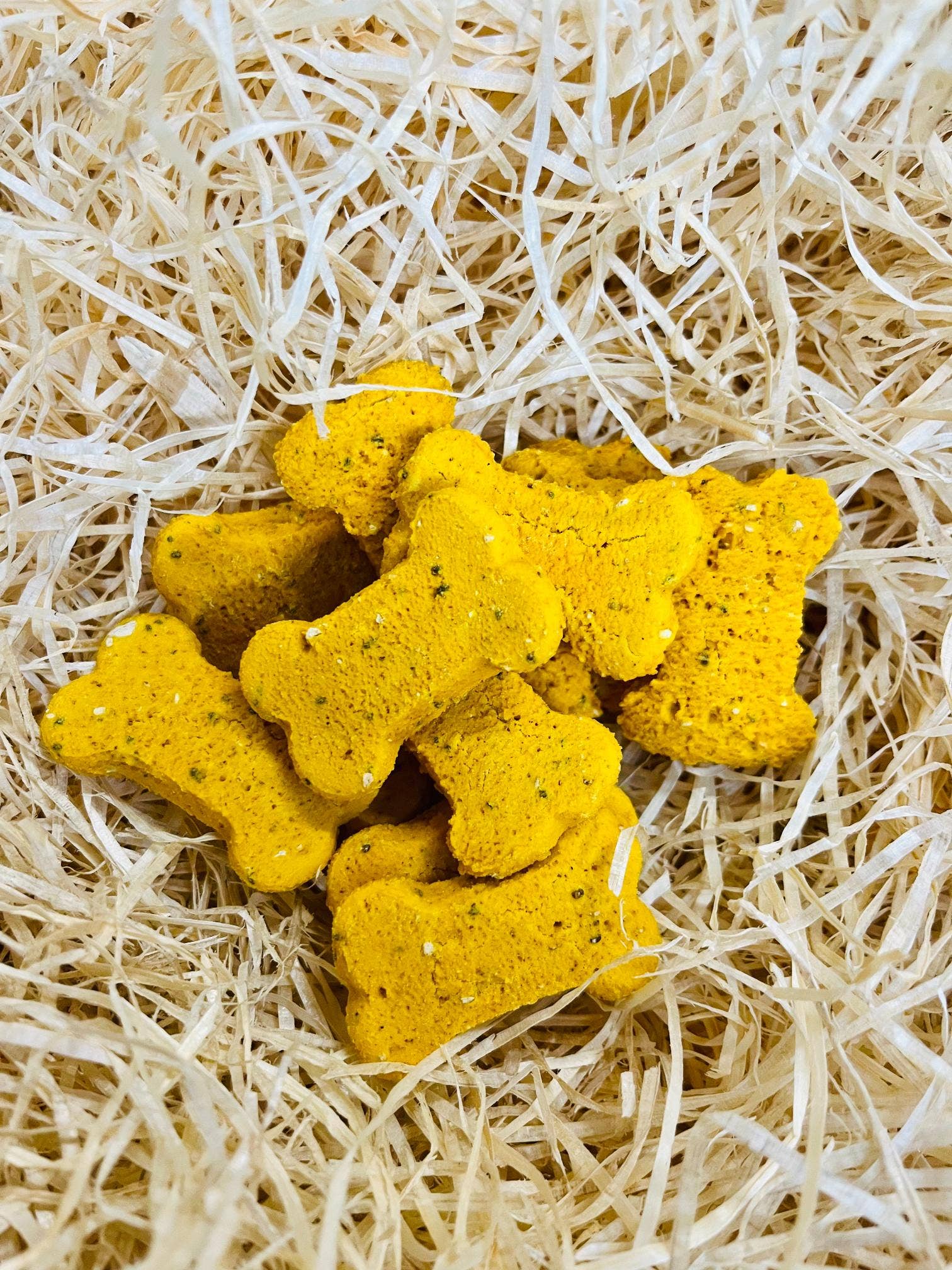 Hip & Joint Bones dog treats displayed loose, crunchy bone-shaped biscuits with turmeric and chia seeds.