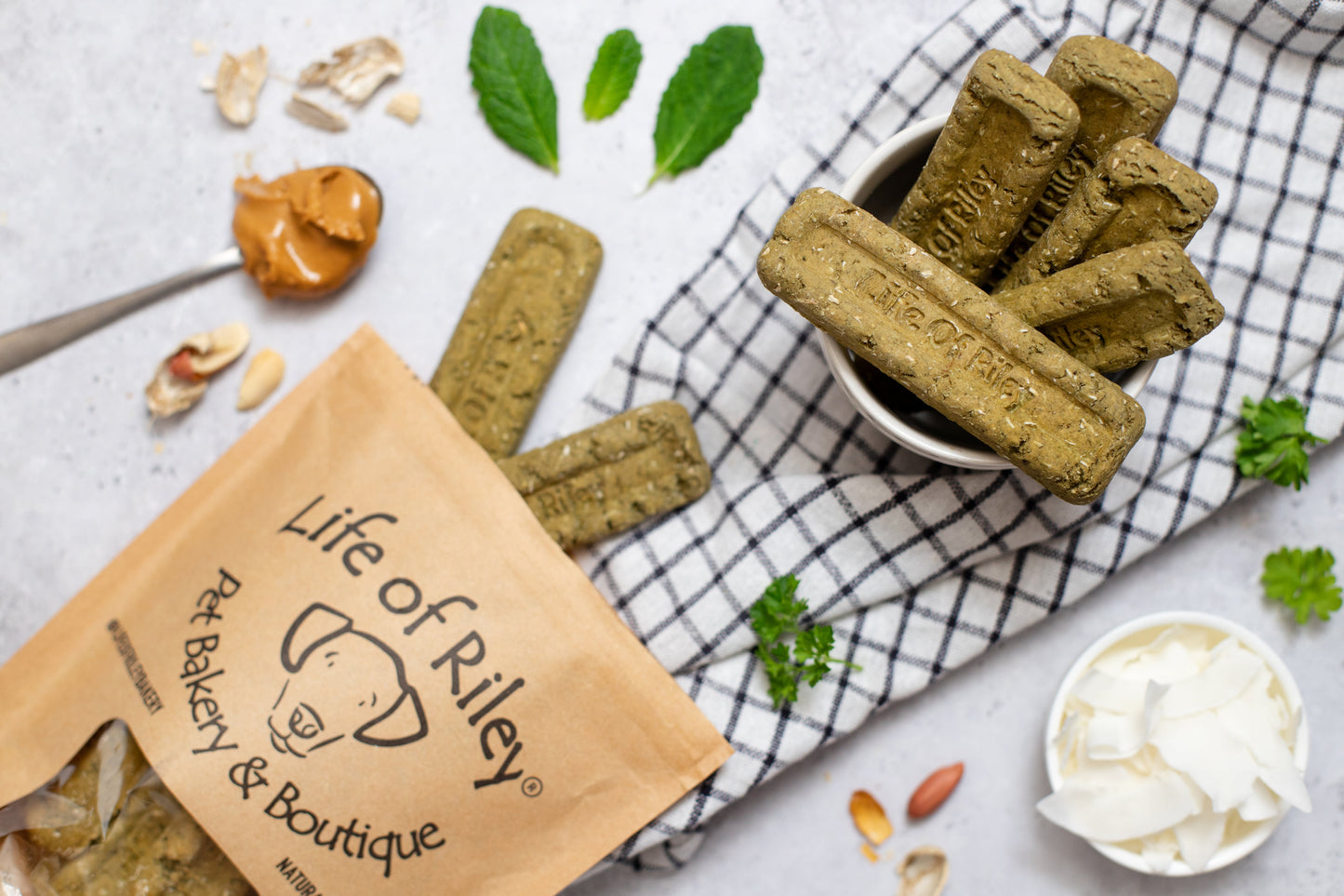 Life of Riley Minty Dental Sticks on a checkered cloth alongside fresh mint, parsley and product packaging — handmade vegan dental treats for dogs