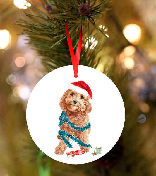 Ceramic Christmas ornament featuring a festive Cavapoo/Cockapoo wrapped in tinsel wearing a Santa hat, hanging from a red ribbon on a decorated Christmas tree.
