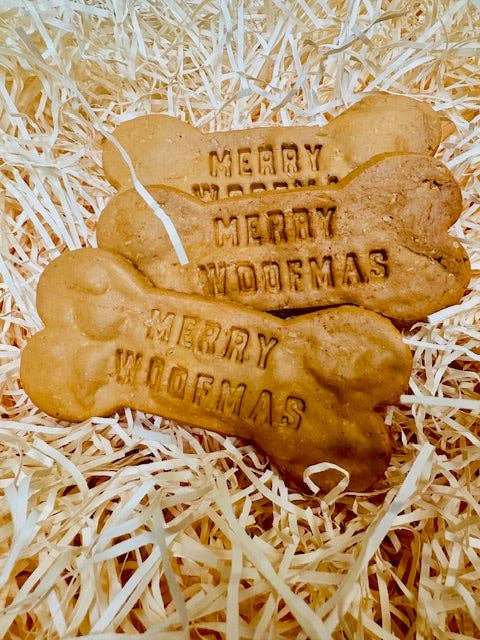 Close-up of Merry Woofmas grain-free peanut-butter dog bones on shredded paper background