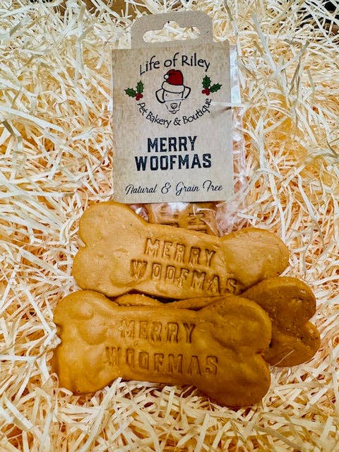 Packaged Merry Woofmas peanut-butter dog bones by Life of Riley Pet Bakery & Boutique on festive shredded paper background