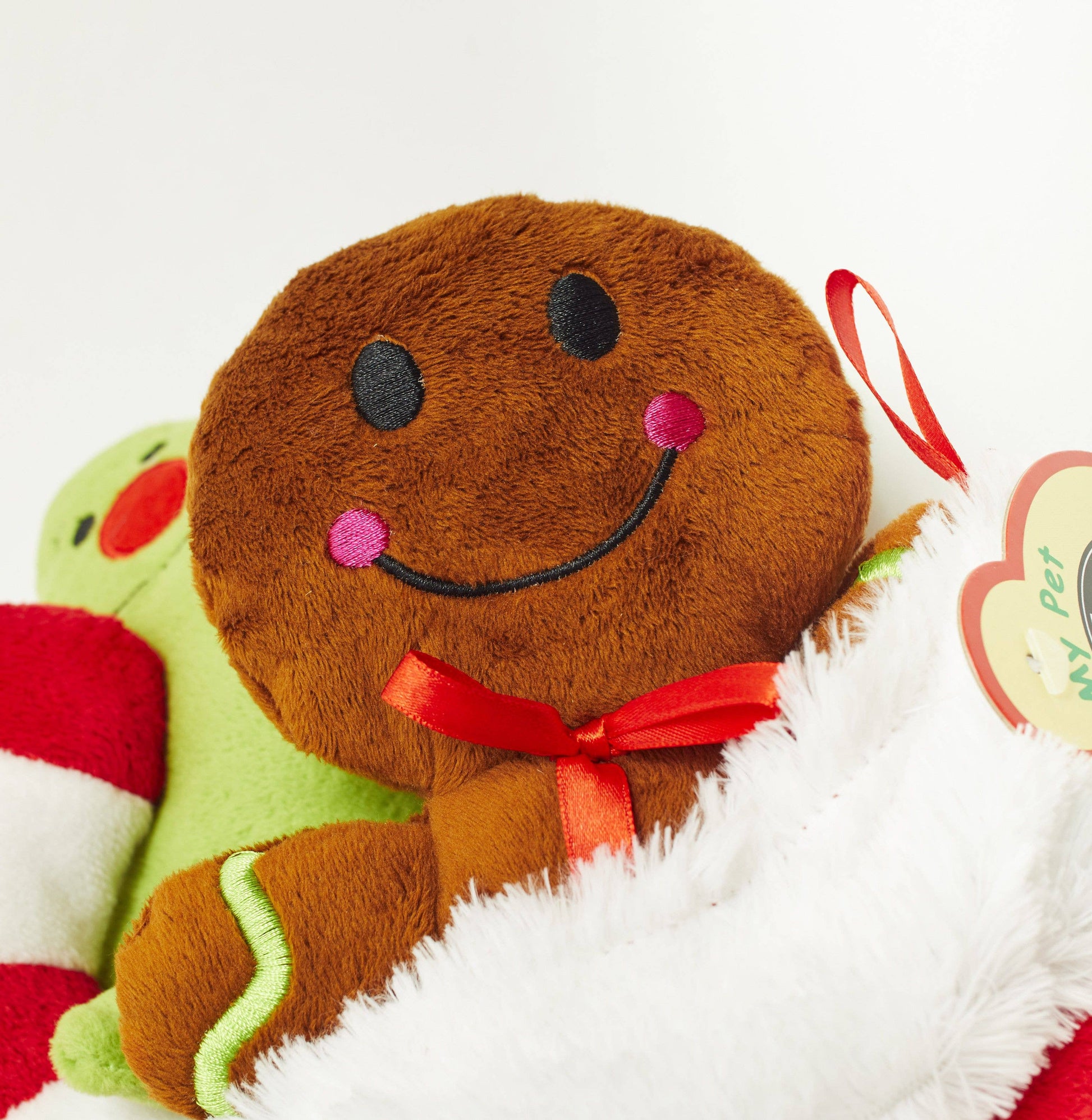 Close-up of PetLondon plush gingerbread man dog toy with red ribbon bow